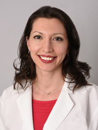 Women wearing red shirt and white lab coat with long brown hair smiling