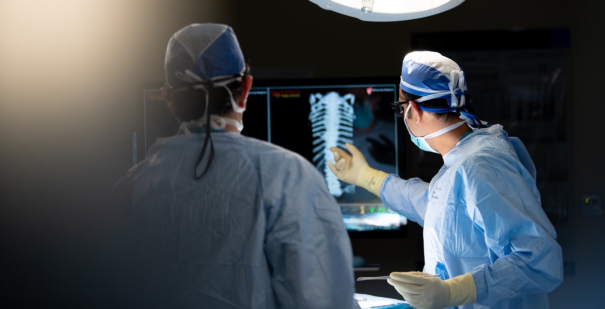 2 physicians looking at an x-ray of a spine