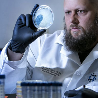 male researcher looking at petri dish