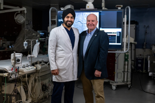 Jim Young standing and shaking hands with his doctor, Devinder Singh, M.D.