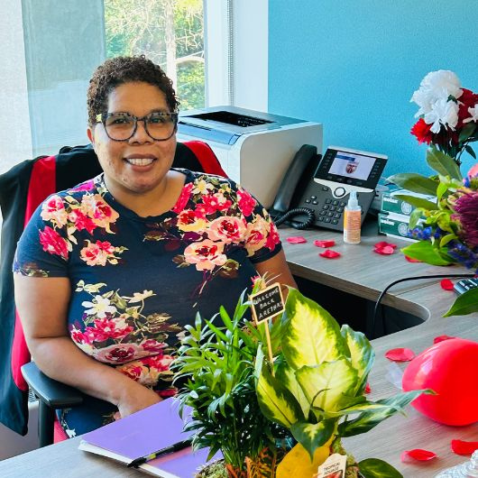 Aretha smiling at her desk on her first day back in the office.