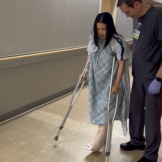 Tram Huynh uses crutches in a hospital hallway.